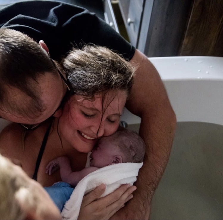 vrouw leunt op partner tijdens bevalling in bad